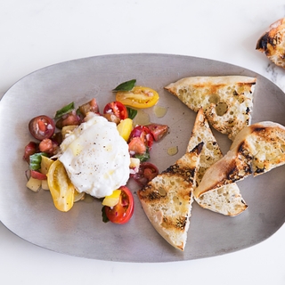 Oval plate of tomatoes and burrata with toasted bread 