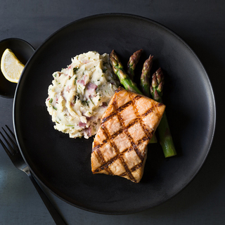 char-grilled salmon fillet with mashed potatoes and steamed broccoli on a black plate