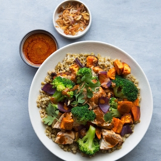 chermoula chicken bowl with chicken breasts, sweet potatoes, broccoli and grains in a white bowl