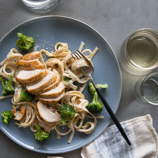 blue plate with fettuccine alfredo, chicken breast and steamed broccoli 