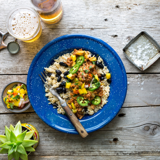 blue plate with brown rice and chicken picadillo bowl with fresh herbs on a wooden table