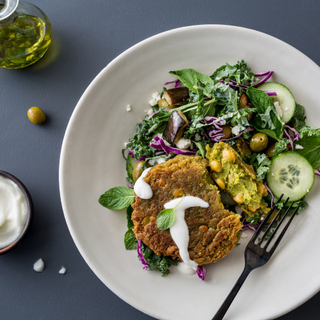 salad with a chickpea cake and white dressing in a white bowl with a black fork