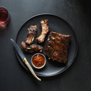 BBQ baby back ribs on a black dinner plate