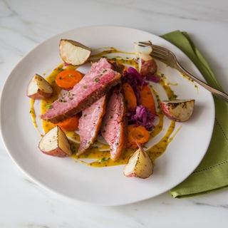 White plate of sliced corn beef on cabbage with carrots 