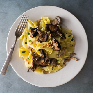 creamy three mushroom pappardelle pasta on a white plate with a silver fork