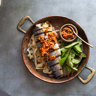 grilled branzino fillet with roasted red pepper relish, greens and braised fennel in a copper pan