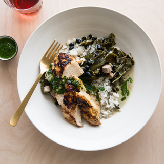 white bowl with chimmichurri chicken breast and coconut milk-braised collard greens with rice and beans