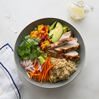 honey chipolte chicken salad with quinoa, sliced chicken breast, avocado, carrots and fresh herbs in a bowl