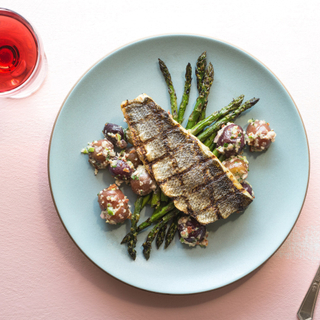 seared branzino fillet on a plate with asparagus and potato salad