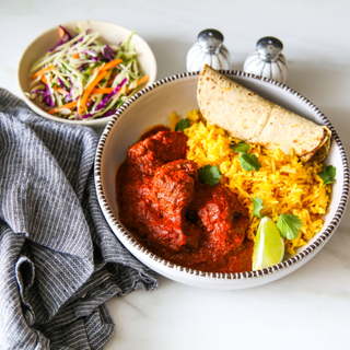 mexican braised lamb with saffron rice and a tortilla in a large white bowl