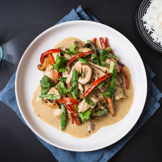 panang chicken curry on a white plate with red peppers, green beans and white steamed rice