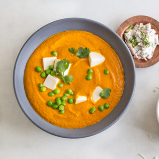 paneer tikka masala in an orange sauce with green peas and fresh cilantro 