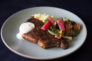 pastrami-rubbed new york strip steak on a plate with beet salad, horseradish cream and mashed potatoes