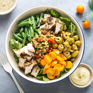 bowl with green beans, chopped chicken breast, cherry tomatoes and green olives with salad greens