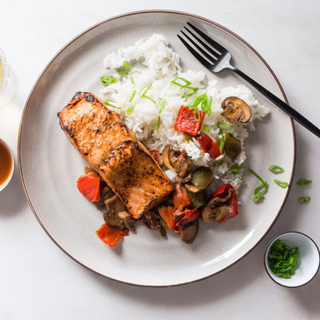 pineapple-ginger glazed salmon fillet with white rice and roasted vegetables on a white plate. 