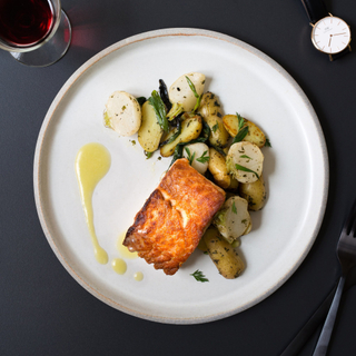 salmon fillet with ginger-miso sauce, roasted potatoes and turnips on a white dinner plate