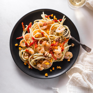 shrimp alfredo with bucatini and parmesan cream sauce on a black plate