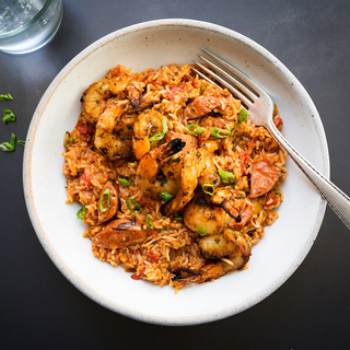 shrimp and andouille sausage jambalaya with rice and scallions in a white bowl