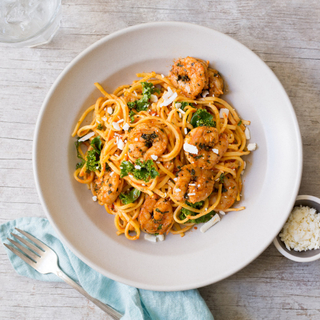 shrimp fra diavolo with linguine pasta and ricotta salata cheese in a white bowl