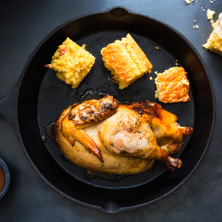 half roasted chicken on a large plate with a side of mac and cheese, a green salad and mustard barbecue sauce in a dish.  