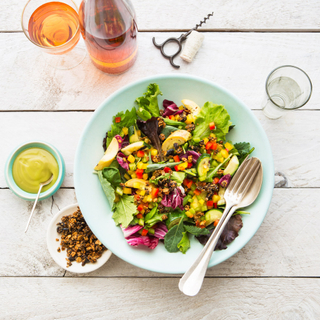 superfood kale salad with avocado and dressing on a white plate with a black fork