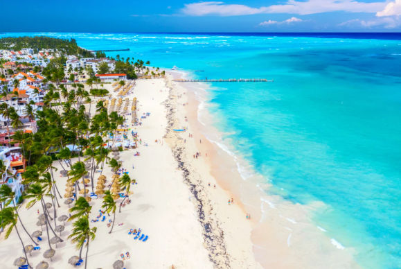 Aerial view of a beautiful white sand beach with palm trees, resorts, and turquoise water in Punta Cana