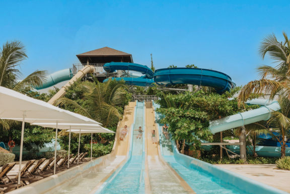 People sliding down tall water slides at a tropical resort water park