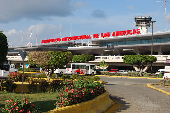 Exterior view of Las Americas International Airport (SDQ) terminal in Santo Domingo, Dominican Republic, with taxis and 24-hour transportation buses.