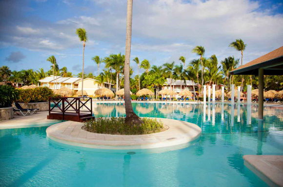 Luxury all inclusive resort swimming pool in Punta Cana with palm trees and tropical villas