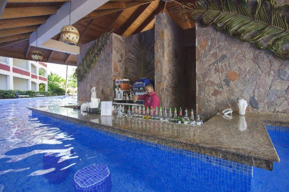 Bartender mixing drinks at a luxury swim-up pool bar in a resort