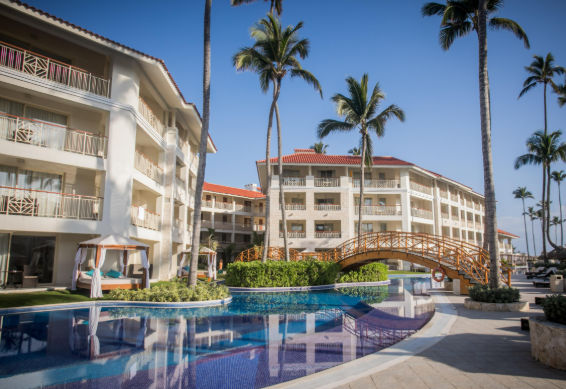 Majestic Resort Punta Cana large swimming pool with wooden bridge, palm trees, and luxury hotel buildings