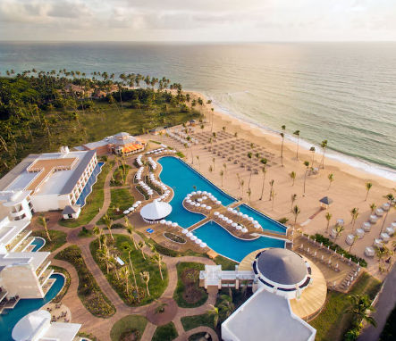 Aerial view of a large beach resort with swimming pools and palm trees at sunset