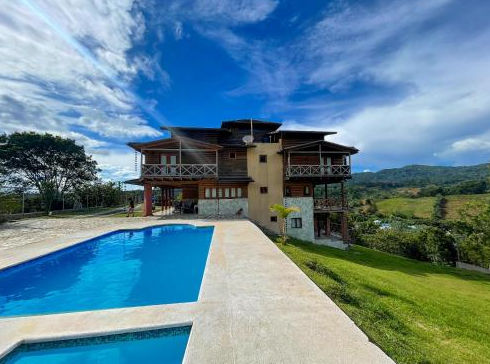 A rustic multi-story house with wood and brick siding, built on a grassy hill