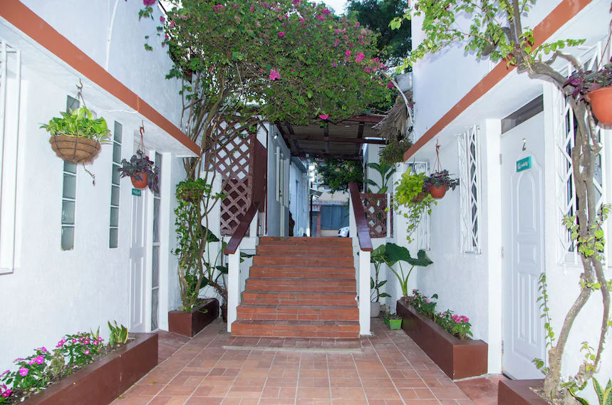 Inner courtyard at Hotel Restaurant Wuarao featuring terracotta stairs, hanging plants, and tropical flowers in Boca Chica.