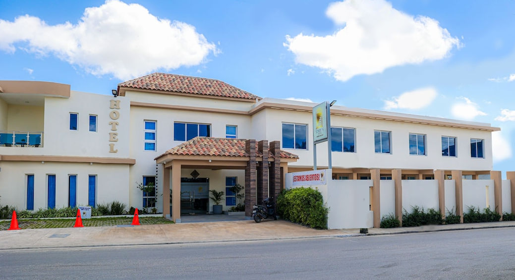 Exterior facade of Jomy's Hotel under a blue sky, showing its main entrance, signage, and a 'We are open!' banner