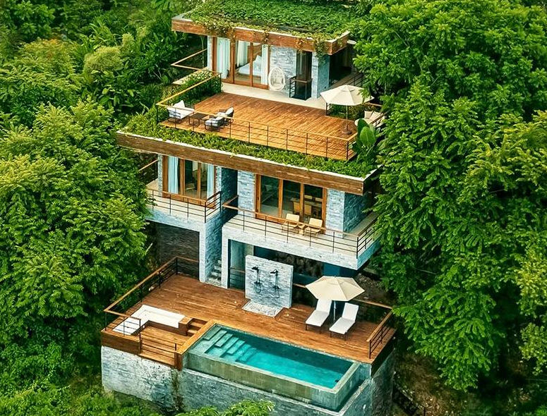 Aerial view of a modern luxury villa at Ocama, Las Galeras, surrounded by dense tropical vegetation with wooden decks, a private pool, and a panoramic view of the sea