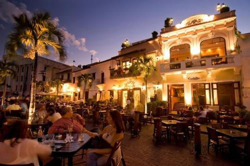 Outdoor restaurant seating in a lit square within the Colonial Zone of Santo Domingo at night
