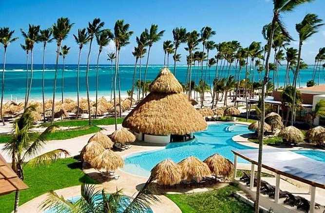 Hermoso resort tropical con piscina, palapas, palmeras y vista al mar Caribe