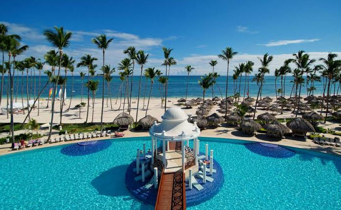 Vista panorámica de piscina infinita y palmeras en resort de playa