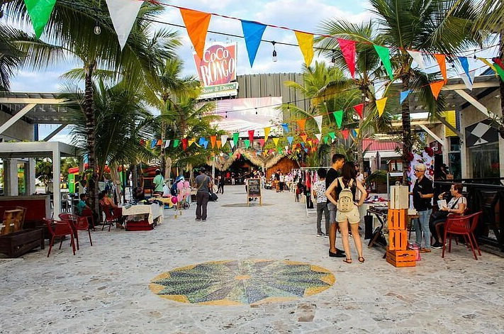 Plaza peatonal en Downtown Punta Cana decorada con banderines festivos de colores y el letrero de Coco Bongo al fondo