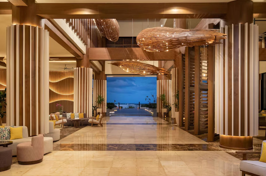 Majestuoso lobby del resort Dreams Punta Cana con diseño tropical de madera, lámparas colgantes y vista al exterior