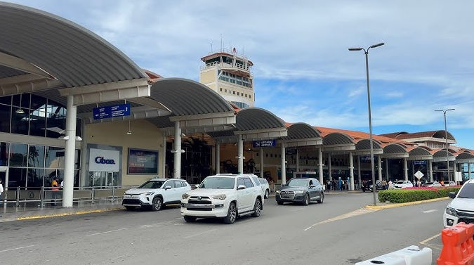 Exterior view of Cibao International Airport (STI) with cars and control tower in Santiago, Dominican Republic