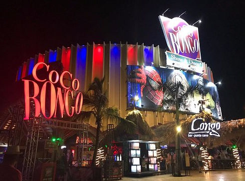 Brightly lit exterior of Coco Bongo nightclub and Congo Bar in Punta Cana at night with red neon signs.