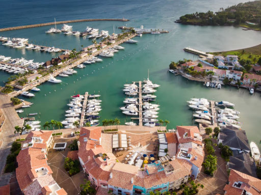 Vista aérea de una exclusiva marina con múltiples yates atracados y pintorescos edificios de estilo mediterráneo con techos de tejas