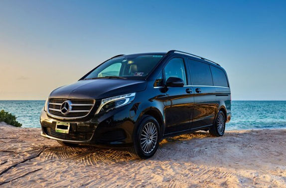 Black luxury executive van parked on a scenic coastal beach for corporate transportation in Santo Domingo