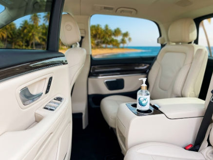 Clean and sanitized luxury taxi interior with hand sanitizer and a tropical beach view