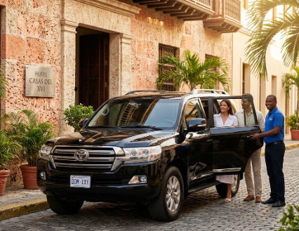 A uniformed driver opens the door of a black luxury SUV for a couple arriving at Hotel Casas del XVI in the Dominican Republic