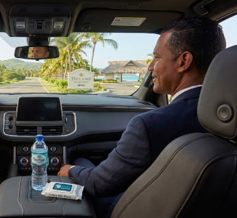 Interior of a luxury private transfer vehicle arriving at Dreams Macao Beach with a professional driver, water, and wet wipes.