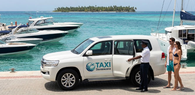 White Taxi Dominicana SUV at Bayahibe marina with a driver opening the door for a couple, boats and Saona Island in the background