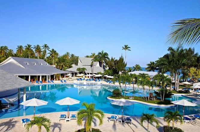 Main entrance to the Gran Bahia Principe San Juan resort with international flags and palm trees
